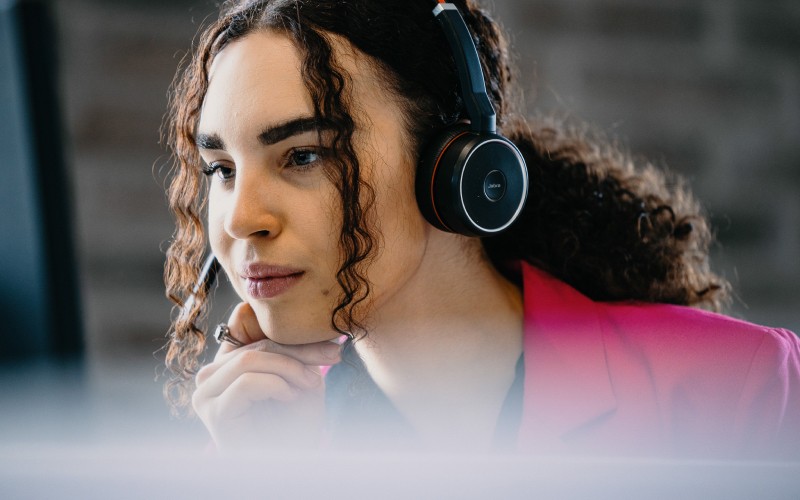 The image: woman with the headphones looks at the screen