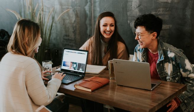 three students in a coffee shops discussing