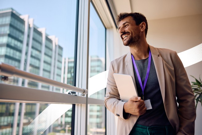 Valamis Leadership onboarding blog featured image of a man standing in the office looking out of the window