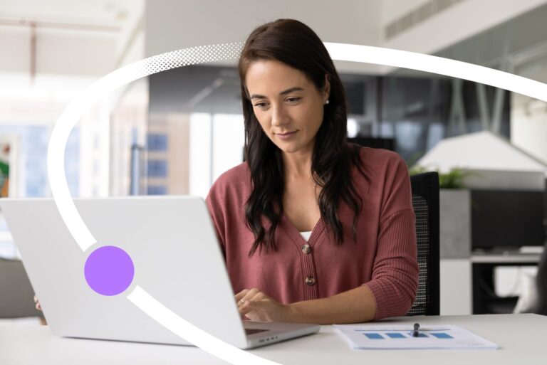 Woman working on a laptop at her desk in a bright open-plan office