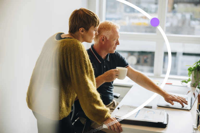 A manager and employee reviewing learning and development plans together at a laptop in a modern office