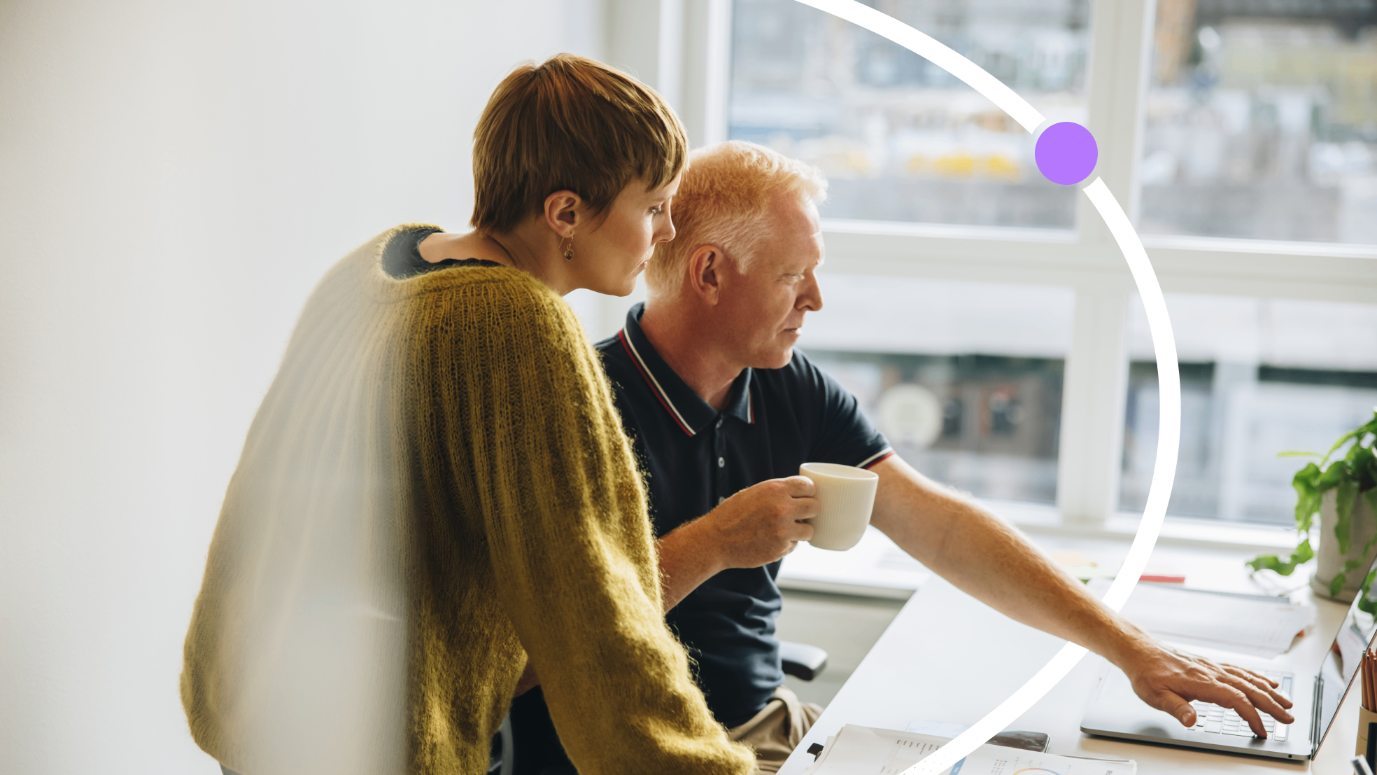 A manager and employee reviewing learning and development plans together at a laptop in a modern office
